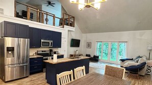 A spacious kitchen with modern appliances, a dining area with wooden furniture, and a loft with a balcony.