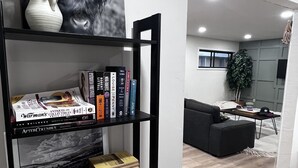 Un soggiorno moderno con una libreria nera, un vaso bianco con una pianta e un quadro in bianco e nero.