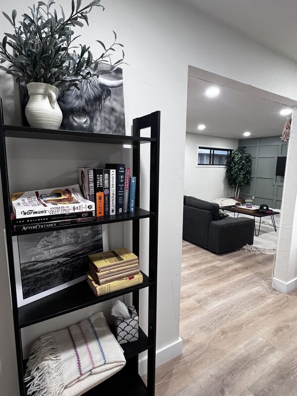 Un salon moderne avec une bibliothèque noire, un vase blanc contenant une plante et un tableau en noir et blanc encadré.