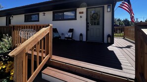 Une terrasse en bois avec une pancarte de bienvenue, une porte ornée d’une guirlande et un drapeau américain.
