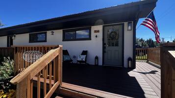 Une terrasse en bois avec une pancarte de bienvenue, une porte ornée d’une guirlande et un drapeau américain.