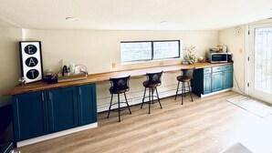 Une cuisine moderne avec des armoires de couleur turquoise, un plan de travail en bois et des tabourets de bar.