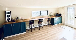 Une cuisine moderne avec des armoires de couleur turquoise, un plan de travail en bois et des tabourets de bar.