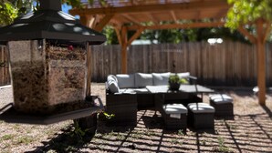 Una zona patio con una pergola, mobili da esterno e un portabirdfeeder.