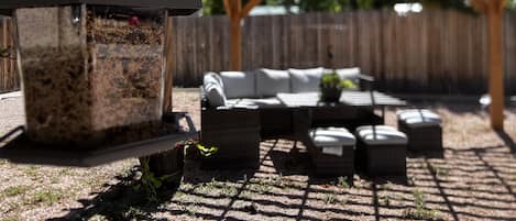 Un patio con pérgola, mobiliario exterior y un comedero para pájaros.