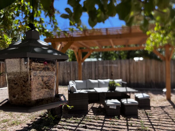 A patio area with a pergola, outdoor furniture, and a bird feeder. - La Veta School House  (La Veta)