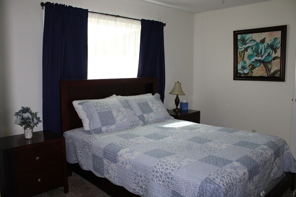 A bedroom with a bed, a nightstand, a lamp, a vase with flowers, and a painting on the wall. - First Monday ~ Brasher Family Farm: Roughly 6 miles to First Monday (Grand Saline)