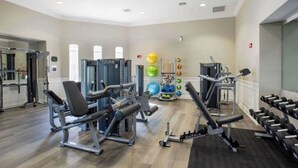 Un gimnasio con diversas máquinas de ejercicio, pesas y pelotas de entrenamiento.