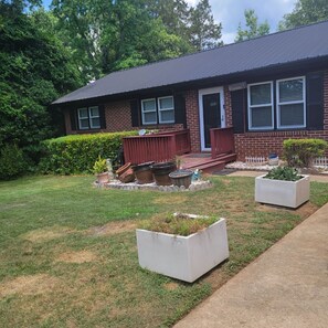 Enjoy the serene atmosphere of this charming home, surrounded by lush greenery and a beautifully manicured lawn.