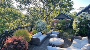A patio with wicker furniture, a round table, and a variety of plants. - Beautiful views, quiet space (Victoria)
