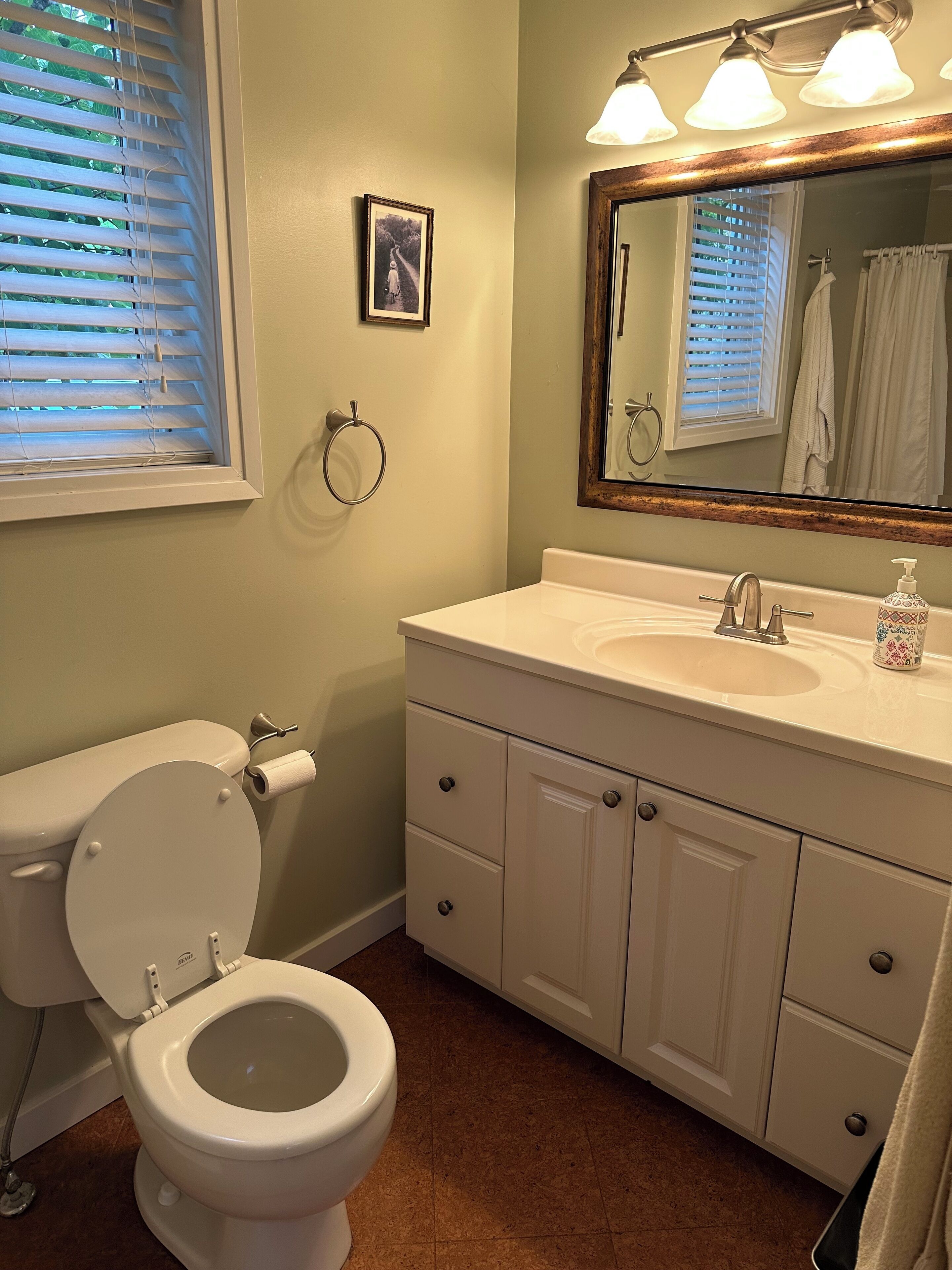 Une salle de bain avec des toilettes, un lavabo et un miroir.
