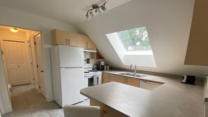 A modern kitchen with a skylight, white appliances, and a bar stool. - Beautiful views, quiet space (Victoria)