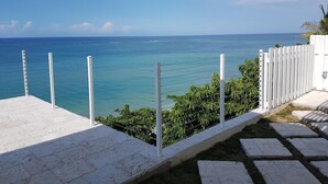 A coastal view with a white fence and a paved area leading to the sea. - The Happy Place- 4BR Beachfront Fully Staffed Villa w/ Eternity Pool (Montego Bay)