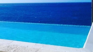 A clear view of a swimming pool with a view of the ocean. - The Happy Place- 4BR Beachfront Fully Staffed Villa w/ Eternity Pool (Montego Bay)