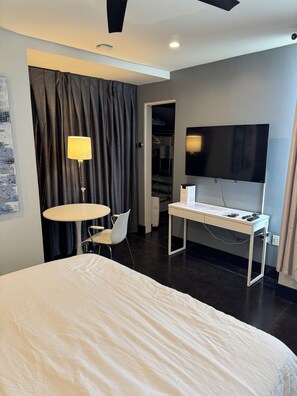 A modern hotel room with a bed, a desk, a chair, a lamp, a TV, and a wardrobe. - eos Haus :Architect-Designed Private Suite • 1 Mile to Ocean Beach (San Diego)