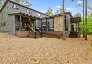 A two-story building with a covered porch and a stone accent wall. - Luxury Mountain Cabin Retreat in Broken Bow (Broken Bow)