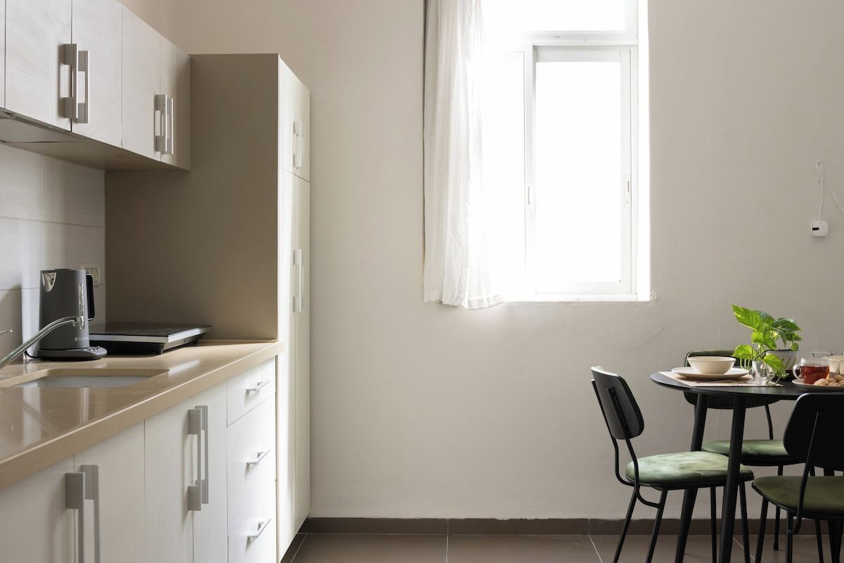 Una cocina con comedor, ventana y una planta.