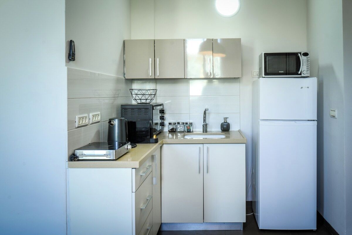 Cocina pequeña con microondas, tostadora y refrigerador.