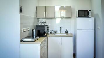 Cocina pequeña con microondas, tostadora y refrigerador.