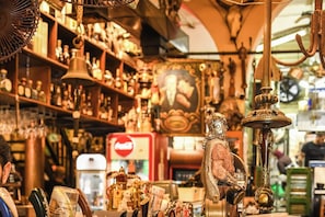 A cluttered antique shop with various items on display, including a bell, a statue, and a Coca-Cola refrigerator.