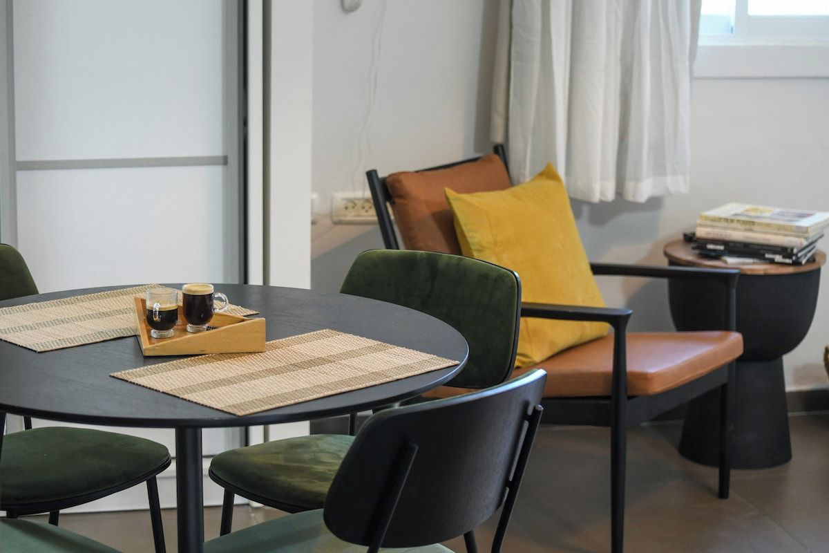 Un comedor con una mesa redonda, sillas y una mesita auxiliar con libros.