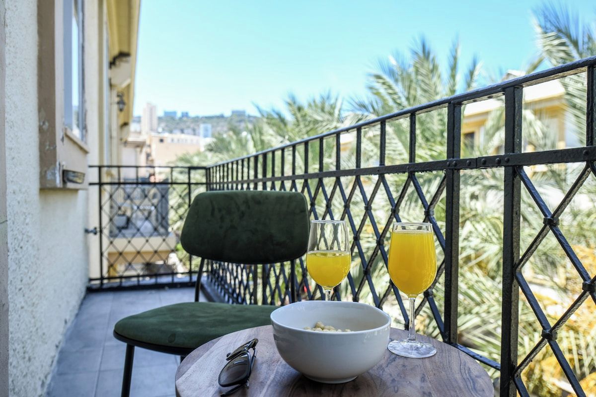 Un balcón con una mesa, un cuenco y dos vasos de jugo de naranja.