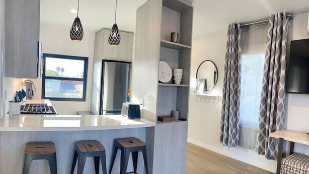 A modern kitchen with a central island, bar stools, pendant lighting, and a built-in oven. - Stunning Ocean Beach Gem - has everything! (San Diego)