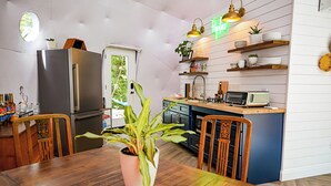 A modern kitchen with a wooden dining table, a refrigerator, and a microwave. - Stargazing Geodome Retreat Outdoor Tub + Mountain View’s (Madisonville)