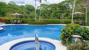 A swimming pool with a hot tub, surrounded by greenery and outdoor seating. - Stylish Apartment w/ Hotel Amenities @ Los Sueños (Playa Herradura)