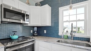 A kitchen with white cabinets, a stainless steel microwave, a blue kettle, and a coffee maker. - West End Gulls~ Guest Favorite ~ Beach Access ~ Astonishing Views (Oak Island)
