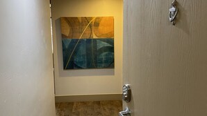 Ein Flur mit Holzboden, einer Tür mit einer Nummernschild und einem an der Wand befestigten Kunstwerk.