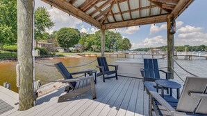 A covered wooden deck with seating and a view of a water body. - Pet-Friendly Lake Norman Home with Boat Dock! (Mooresville)