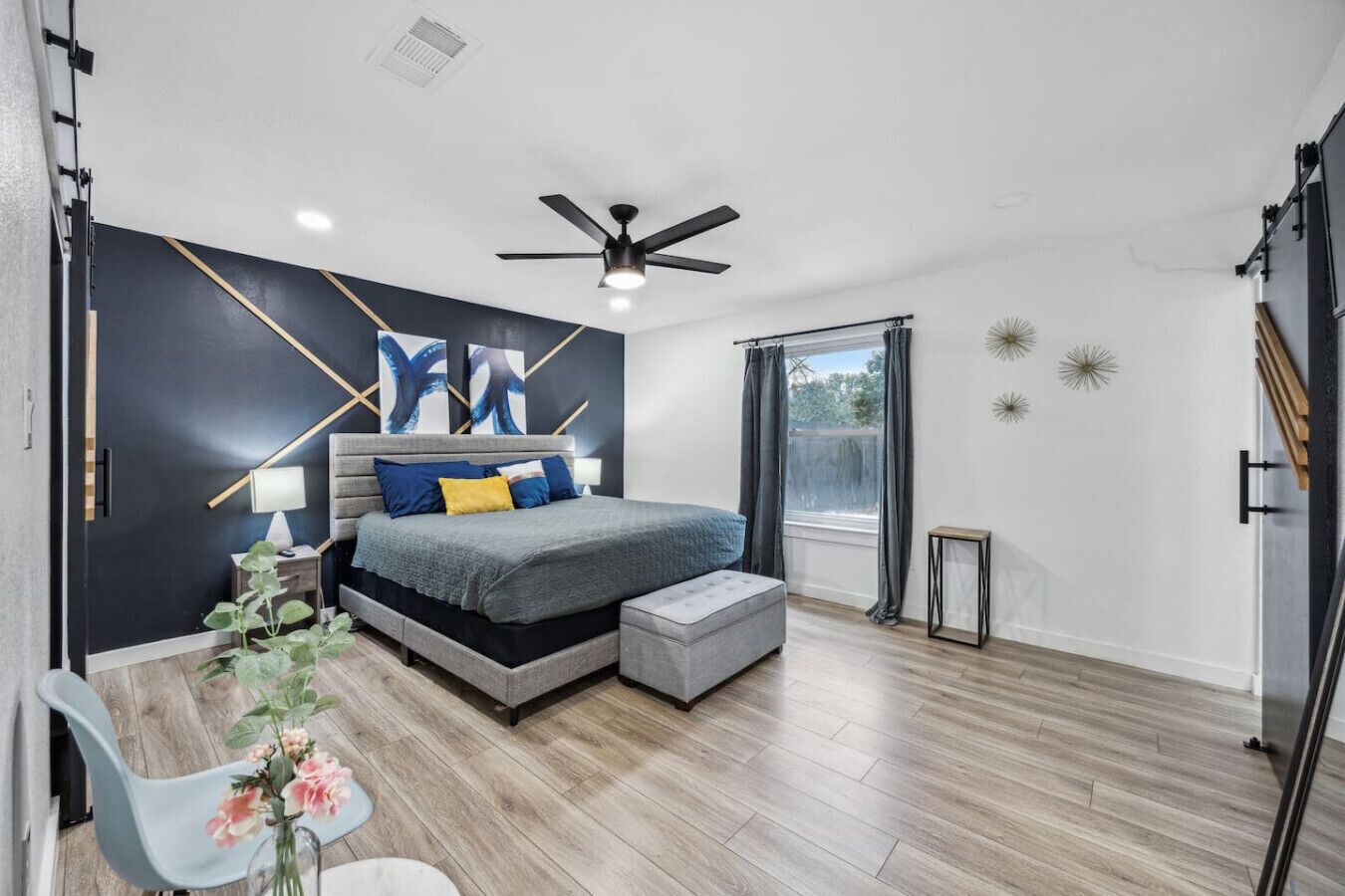 A modern bedroom with a bed, bedside table, and a ceiling fan.