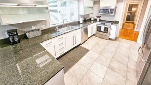 A modern kitchen with granite countertops, stainless steel appliances, and white cabinetry.