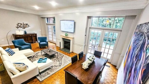 A spacious living room with a fireplace, a dining area, and a large window offering a view of greenery.