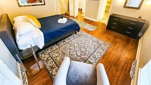 A bedroom with a bed, a chair, a dresser, and a television.
