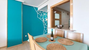 A dining area with a teal wall, a geometric white accent wall, and a wooden dining table with woven placemats. - Pet friendly apartment in Oropesa del Mar (Oropesa del Mar)