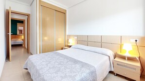 A hotel room with a bed, bedside tables, a wardrobe, and a door leading to another room. - Pet friendly apartment in Oropesa del Mar (Oropesa del Mar)