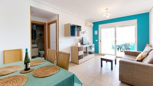A living room with a teal table, a sofa, and a TV. There is a balcony with chairs and a table. - Pet friendly apartment in Oropesa del Mar (Oropesa del Mar)