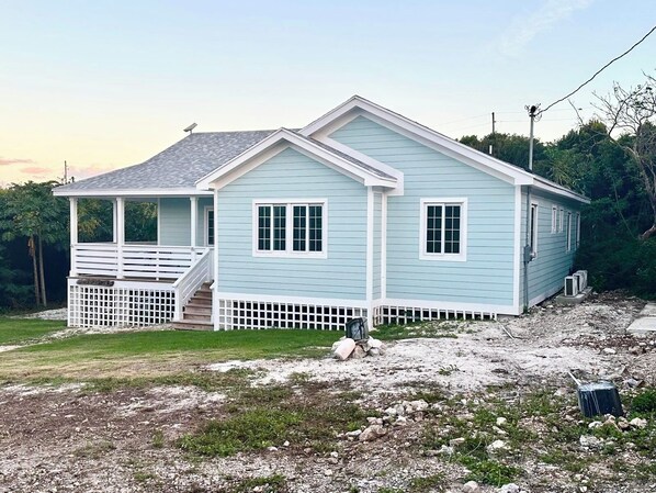 A light blue single-story house with a covered porch and a small staircase leading to the entrance.