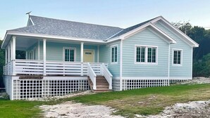 A light blue house with a porch and a small staircase leading to the front door. - Sands of Time is ready for You  (Rainbow Bay)