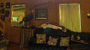 Una habitación acogedora con techo de madera, una ventana, chimenea y un sofá con cojines de motivos animales.