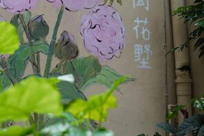 A wall with a floral mural and some Chinese characters. - Yangshuo Yijian Huashu Inn (West Street) (Yangshuo)