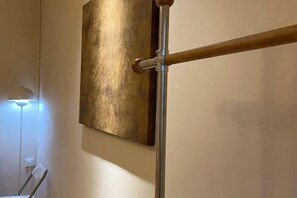 Un objeto metálico fijado a la pared, posiblemente un radiador, con un asa de madera.