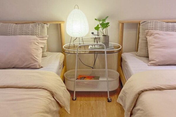 A hotel room with two beds, a bedside table with a lamp, a small plant, and a basket. - Yangshuo Yijian Huashu Inn (West Street) (Yangshuo)