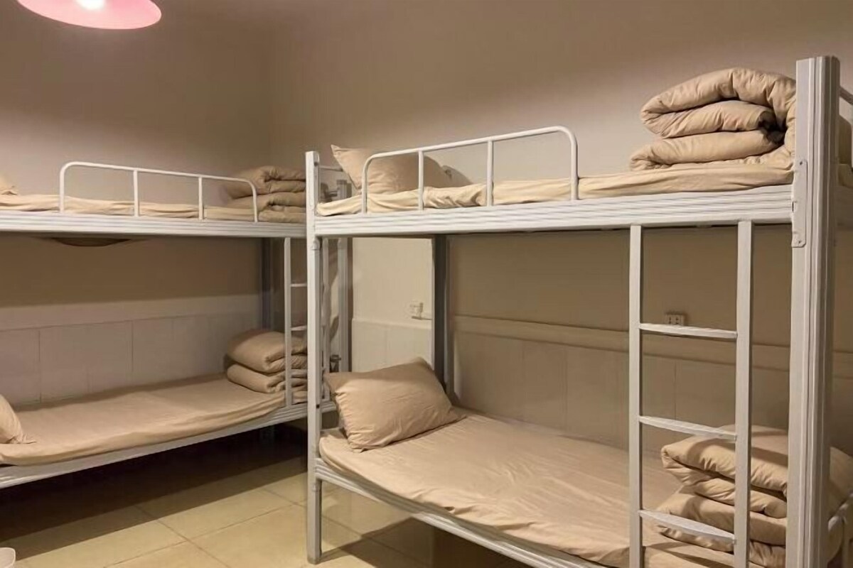 Un dormitorio con literas, cada una con colchón y almohadas.