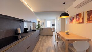 A modern kitchen with a built-in stove, a sink, and a dining area with a wooden table and chairs. - Casa Camelia: your luxury apartment in the heart of Cinque Terre (Volastra)