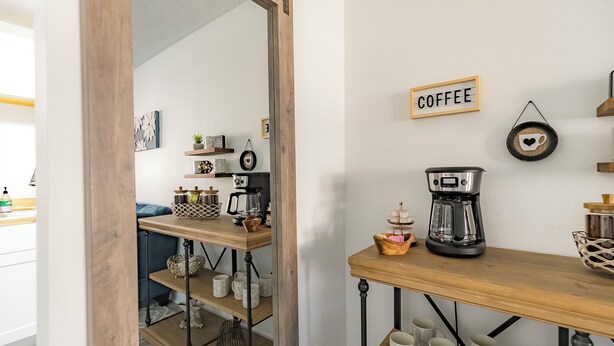 Une cuisine équipée d’un coin café, comprenant une machine à café et des tasses, ainsi qu’un panneau indiquant « CAFÉ ».