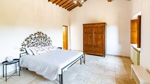 Une chambre à coucher avec un lit, une armoire en bois et un plafond avec des poutres apparentes.