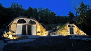 Una casa de piedra con techo curvo y ventanas amplias, rodeada de árboles.